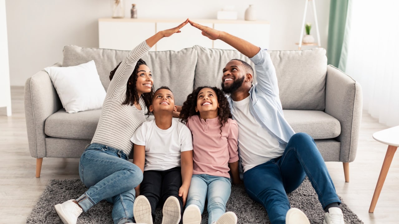 A family seated on the floor in front of their couch, smiling