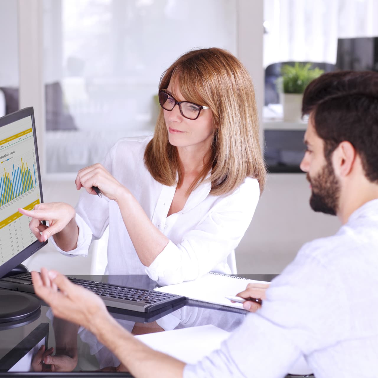 A woman gesturing to graphs on a computer