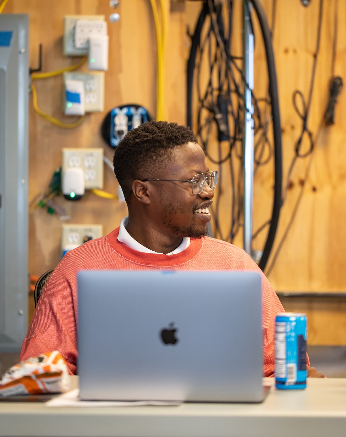 A person utilizing a laptop computer while seated at a desk with electrical wiring components behind them